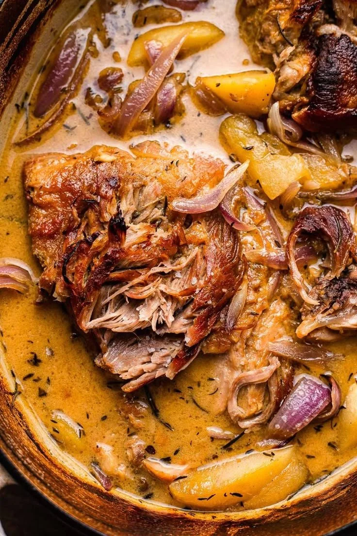 Delicious Apple Cider Braised Pork Shoulder served with herbs and sides.