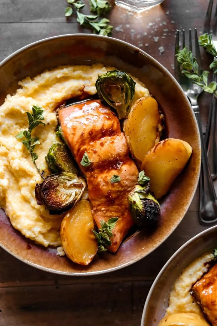 Maple cider glazed salmon with honey butter polenta dish served on a plate.