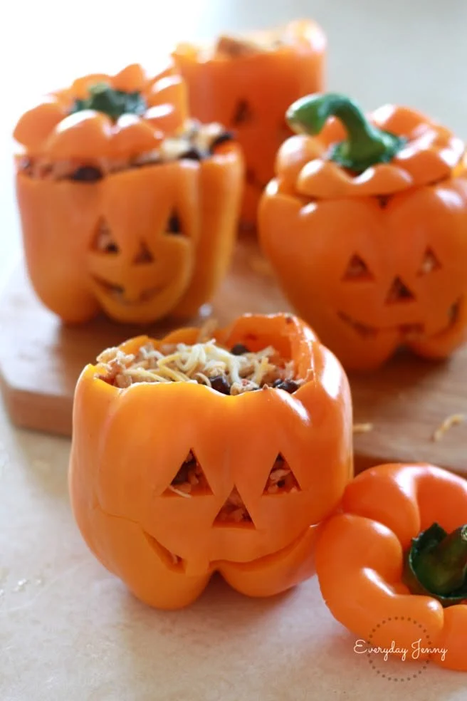 Halloween-themed shredded chicken and rice stuffed peppers on a serving plate.